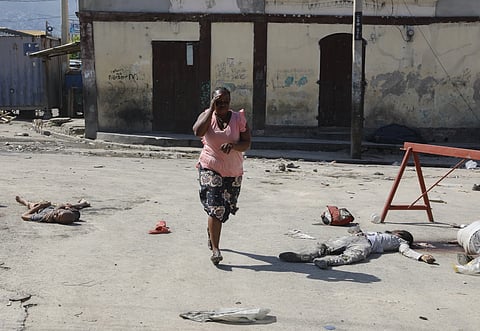 A woman walks past bodies of inmates outside the National Penitentiary in Port-au-Prince, Haiti, Sunday, March, 2024.