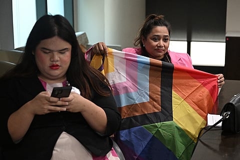 LGBTQI+ gender rights activist Ann Waddao Chumaporn (R) holds a pride flag while in a waiting room with LGBTQ activist and representative of the bill Chanya Rattanatada (L) at Thai Parliament in Bangkok on April 2, 2024.