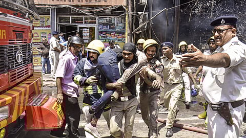 Firefighters rescue an injured person after a fire broke out in a hotel near the Patna Junction railway station, in Patna, Thursday, April 25, 2024.