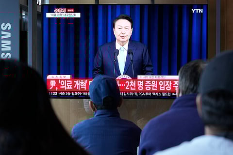 People watch a TV screen showing the live broadcast of South Korean President Yoon Suk Yeol’s addressing the nation at the Seoul Railway Station in Seoul, South Korea.