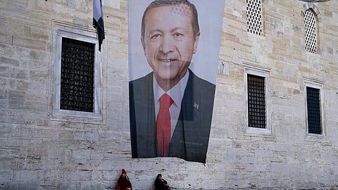 Two women sit near a campaign banner of Turkish President and leader of the Justice and Development Party, or AKP, Recep Tayyip in Istanbul, Turkey, Monday, March 11, 2024.