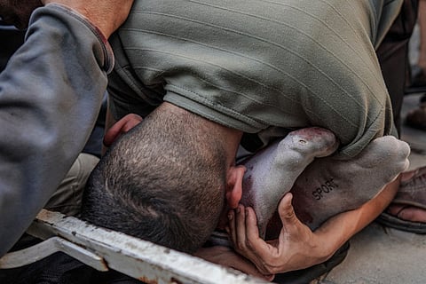 A Palestinian man hugs the feet of a victim of Israeli bombardment in Maghazi, in the central Gaza Strip, on April 16, 2024, amid ongoing battles between Israel and the Palestinian militant group Hamas.