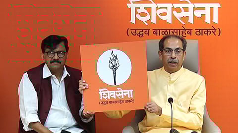 Shiv Sena (UBT) chief Uddhav Thackeray (R) and party leader Sanjay Raut unveil the flaming torch symbol in Mumbai on Tuesday.