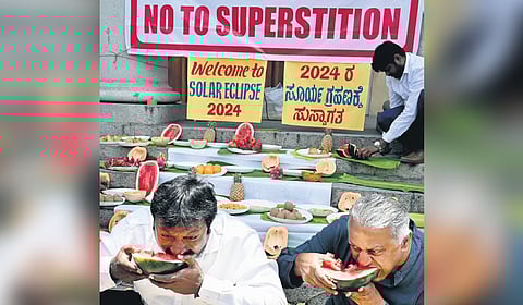 Volunteers eat watermelon during the solar eclipse, to bust myths associated with the celestial phenomenon, in Bengaluru on Monday