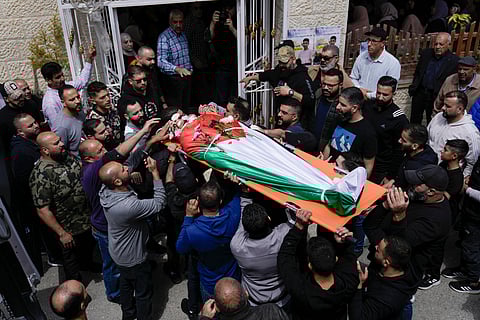 Palestinians gather next to the body of Omar Hamed during his funeral at the village of Beitin, near the West Bank city of Ramallah in the occupied West Bank, Sunday, April 14, 2024. Israeli settlers in the occupied West Bank went on the largest rampage against Palestinians there since the war in Gaza began, as Israel's army said Saturday the body of a missing Israeli teen was found after he was killed in a "terrorist attack."