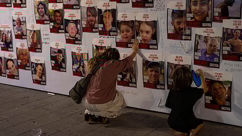 A woman touches photos of Israelis missing and held captive in Gaza, displayed on a wall in Tel Aviv on Oct. 21, 2023.
