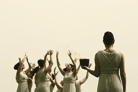 A Greek actress dressed as an ancient priestess, right, holds the Olympic flame during a dress rehearsal for Monday's flame-lighting ceremony, in this stadium of Ancient Olympia, March 23, 2008, where the ancient Olympics were born in 776 B.C.