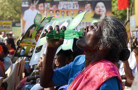 An old lady drinking water to bear the heat