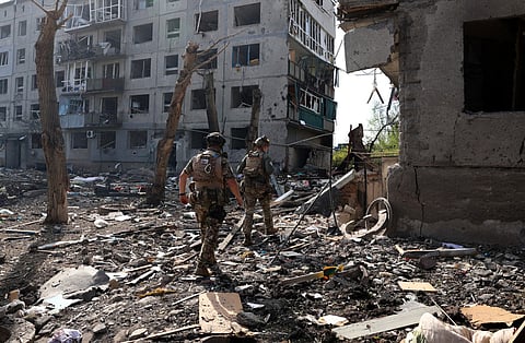 Officers of the special police force "White Angel" Hennadiy Yudin 47(L) and Dmytro Solovyi 23 (R) walk past destroyed buildings and debris during the evacuation of local residents from the village of Ocheretyne not far from Avdiivka town in the Donetsk region, on April 15, 2024, amid the Russian invasion in Ukraine.