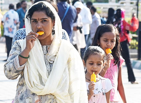 Women and children walking by with ice candy on a hot summer afternoon in Bengaluru.