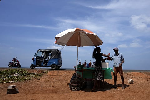 A man buys cool drink from a roadside vendor on a sunny day in Mahawewa, a village north of Colombo, Sri Lanka, Feb 29, 2024.