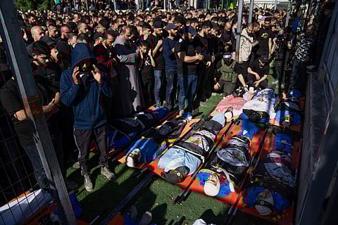 Mourners pray over the bodies of Palestinians, draped in the Islamic Jihad militant group flags, during their funeral in the Nur Shams refugee camp, near the West Bank town of Tulkarem.