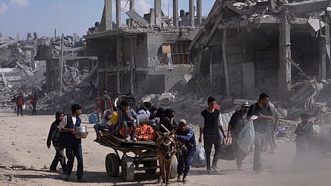 Palestinians walk through the destruction in the wake of an Israeli air and ground offensive in Khan Younis, southern Gaza Strip.