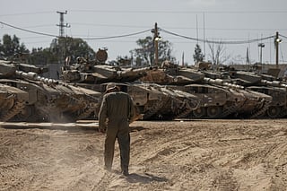 Israeli soldiers work on tanks at a staging ground near the border with the Gaza Strip, in southern Israel, Thursday, April 11, 2024.