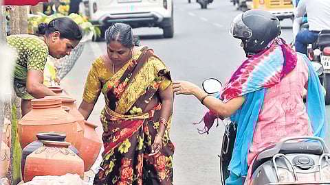 A woman buys earthen water pots from a vendor in Uppal