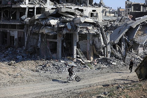 Palestinians walk through the destruction left by the Israeli air and ground offensive after they withdrew from Khan Younis, southern Gaza Strip, Sunday, April 7, 2024.