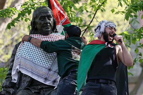 Qais Dana protests as a person puts a scarf on a Ben Franklin statue on Penn's campus during a pro-Palestinian demonstration in Philadelphia on Thursday, April 25, 2024.