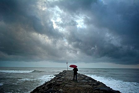 A man walks to the end of groyne at Kothi to enjoy the monsoon rain in Kozhikode.