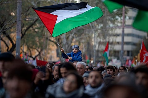 A boy waves a Palestinian flag as demonstrators march during a protest in support of Palestinians and calling for an immediate ceasefire in Gaza, in Barcelona, Spain, on Jan. 20, 2024.