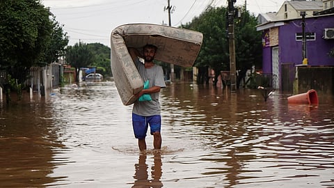 A man, carrying a mattress wades through a flooded street after heavy rains, in Canoas, Rio Grande do Sul state, Brazil.