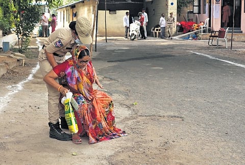 A policewoman helps a voter who has fallen while
arriving at the poll booth at Chudi Bazar in Hyderabad on Monday