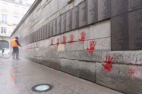 A city employee at work cleaning the "Wall of the Righteous" (Mur des Justes) covered with Red hands graffitis outside the Shoah memorial in Paris, after the monument was vandalized overnight.