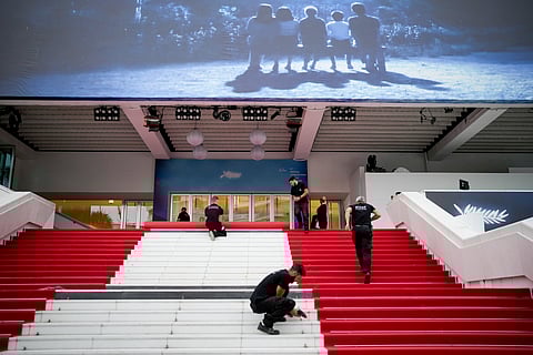Festival workers lay the red carpet at the Palais des Festivals on opening day of the 77th international film festival, Cannes, southern France, Tuesday, May 14, 2024.