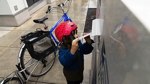 Ramona McCune, 4 1/2 years-old, puts vote-by-mail ballots into a dropbox during primary voting on May 21.