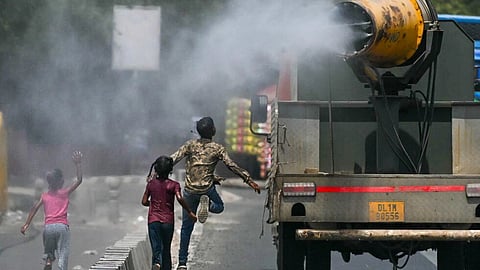 Children run behind a truck spraying water along a street on a hot summer day in New Delhi on Tuesday, May 28, 2024.