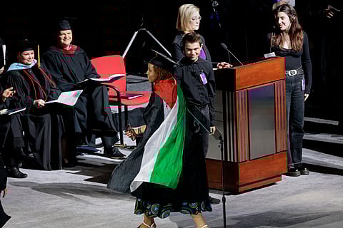 A graduate twirls with her Palestinian flag cape during the Emerson College commencement ceremony at Boston University's Agganis Arena, Sunday, May 12, 2024, in Boston. Many students verbally protested throughout the ceremony.