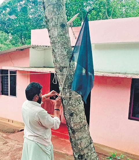 A man hoisting a black flag to protest against the elephant corridor plan in Gudalur.