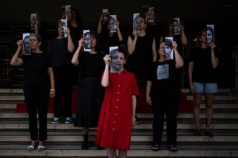 Relatives and supporters of Israeli hostages held by Hamas in Gaza hold photos of their loved ones during a performance calling for their return in Tel Aviv, Israel, Thursday, May 23, 2024.
