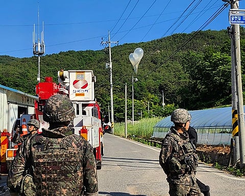 In this photo provided by Jeonbuk Fire Headquarters, balloons with trash presumably sent by North Korea, hang on electric wires as South Korean army soldiers stand guard in Muju, South Korea, on Wednesday, May 29, 2024.