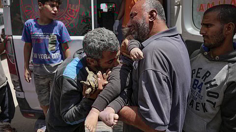 Palestinians hold the body of a dead baby rescued from the rubble of a building destroyed in an Israeli airstrike in Nuseirat, Gaza Strip, Tuesday, May 14, 2024.