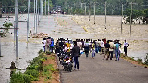 Villagers stand near the flooded portion of a road following rains in the aftermath of Cyclone Remal, in Hojai district, Assam.