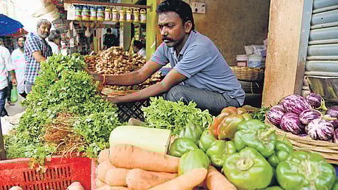 A vegetable vendor arranges fresh produce, as he waits for customers at his shop, in Bengaluru on Wednesday