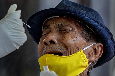 A man reacts as a nasal swab sample is collected from him to test for a Covid in Bangkok, Thailand, Wednesday, May 6, 2020.
