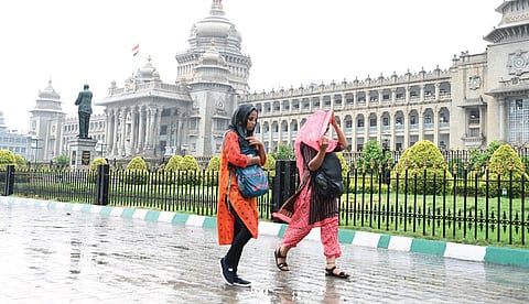 Students enjoy the rain as they walk past Vidhana Soudha on Friday | Express