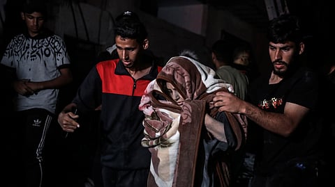 Palestinians rescue a woman survived after the Israeli bombardment on a residential building of Abu Alenan family in Rafah, southern Gaza Strip.