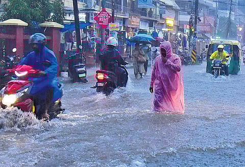Vehicles and pedestrians wade through the inundated arterial road near Changampuzha Park at Edappally