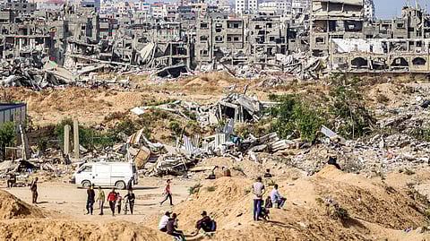 People wait before destroyed buildings in cleared area by the coastline for humanitarian aid packages to drop over the northern Gaza Strip on April 23, 2024.