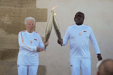 French torchbearers Colette Cataldo, left, and Basile Boli perform a torch kiss during the first stage of the Olympic torch relay in Marseille, southern France, Thursday, May 9, 2024.