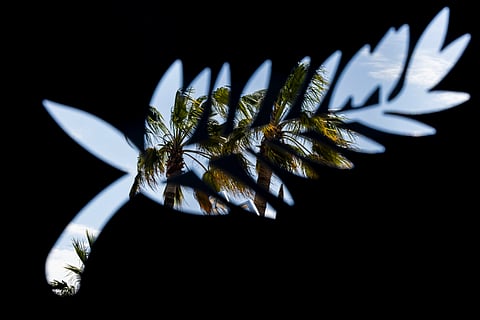This photograph taken on May 13, 2024 shows palm trees through a cutout in the shape of the palm, logo of the Cannes film festival.