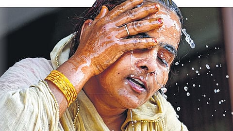 A woman splashes water on her face on a hot summer day amid heatwave, in New Delhi.