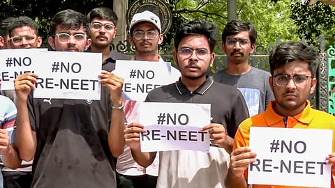 Students hold placards as they stage a protest against the re-examination of the NEET-UG exams, in Rajkot on Sunday.