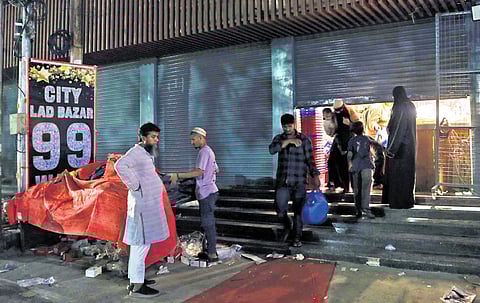 People are seen exiting a shop that is being closed around 10.30 pm at Asifnagar in Old City, Hyderabad on Monday