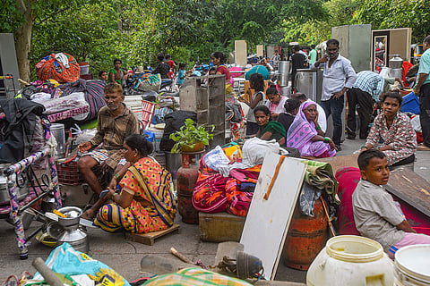 Locals sit with their belongings on a road during an anti-encroachment drive at Jai Bhim Nagar slum colony, Powai, in Mumbai, Thursday, June 6, 2024.