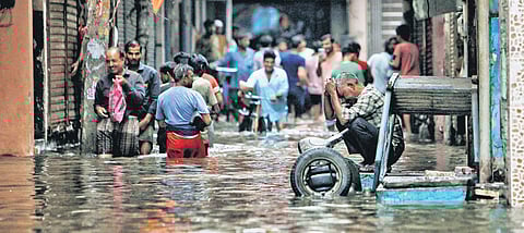 People (left) wade through a waterlogged road near Sarai Kale Khan, New Delhi.| PTI