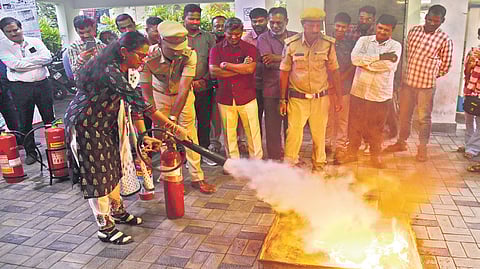 A fire safety official teaches a TNIE staff member how to use a fire extinguisher, during a mock fire drill in Hyderabad on Wednesday