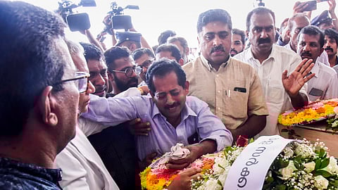 Father Abraham (C) mourns near the mortal remains of Sibin who was killed in a fire incident in Kuwait, at the Cochin International Airport in Kochi, Friday,